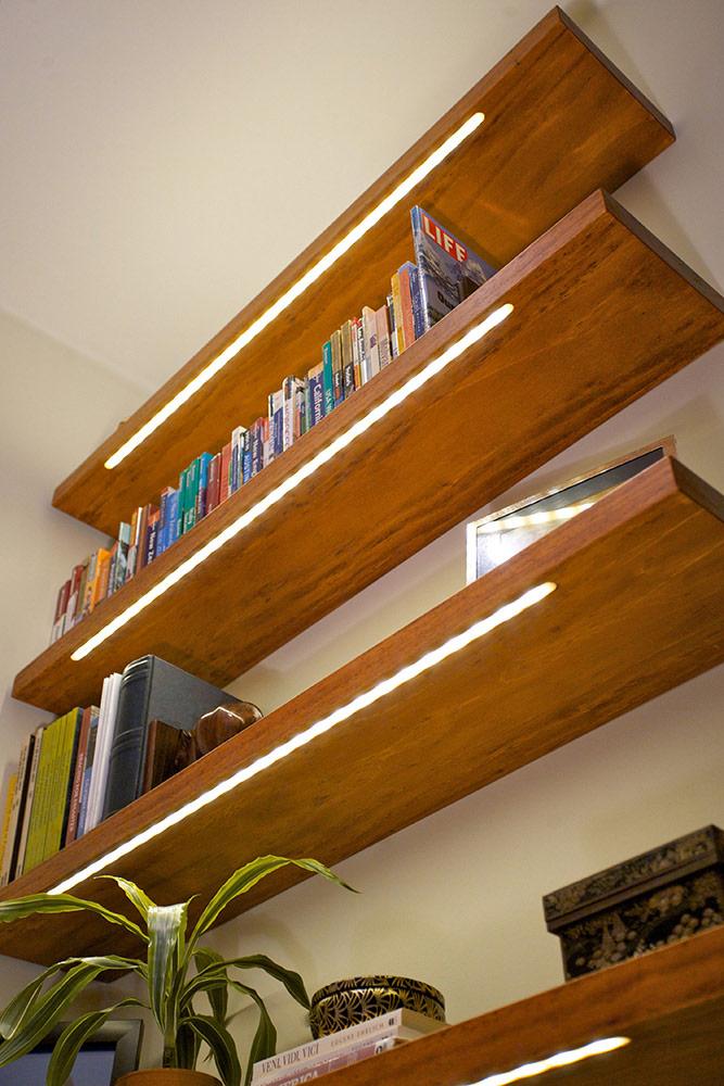 Wooden floating shelves with warm white SMD LED strip lighting illuminating books and decor creating soft accent lighting