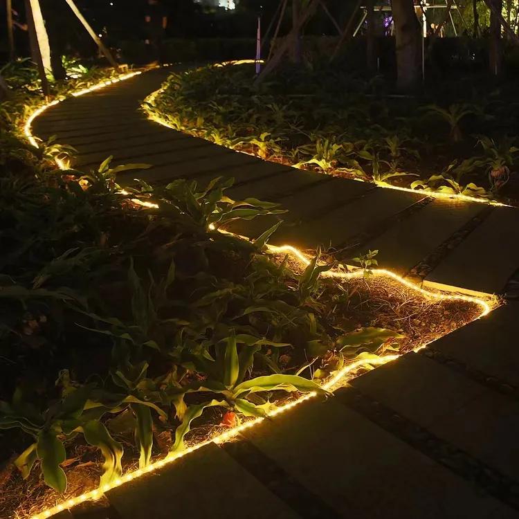 Outdoor garden pathway illuminated with warm white SMD LED strip lighting outlining walkway edges and landscape plants at night